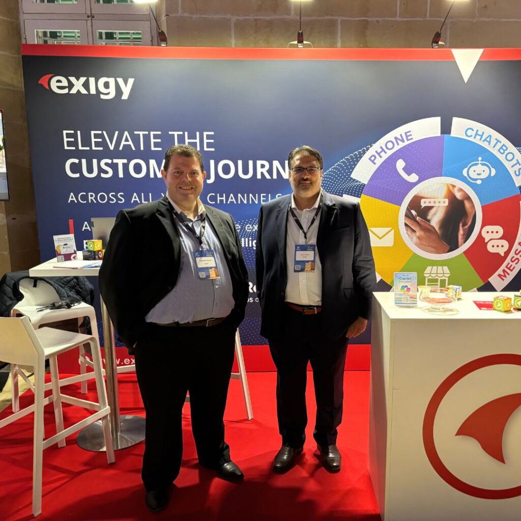 Exigy team members standing at a branded booth promoting omnichannel customer journey solutions at a technology event.