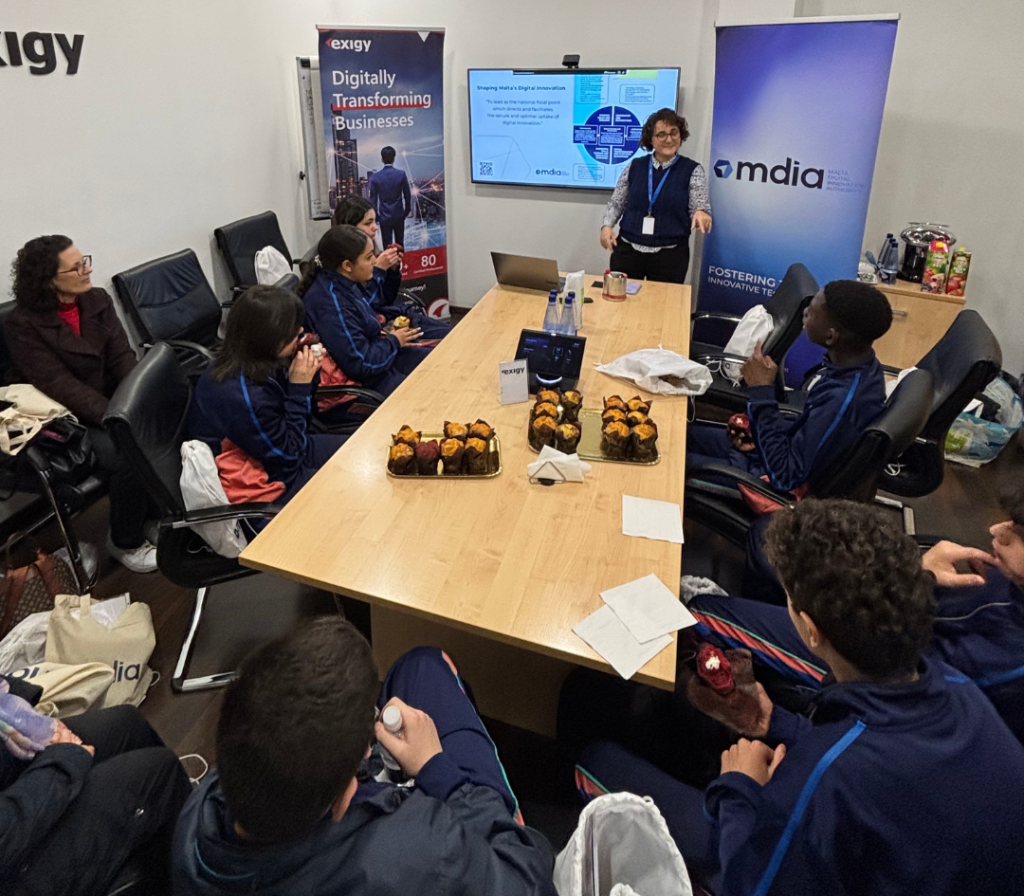 MDIA representative presenting digital innovation strategy to Exigy visitors in a meeting room.