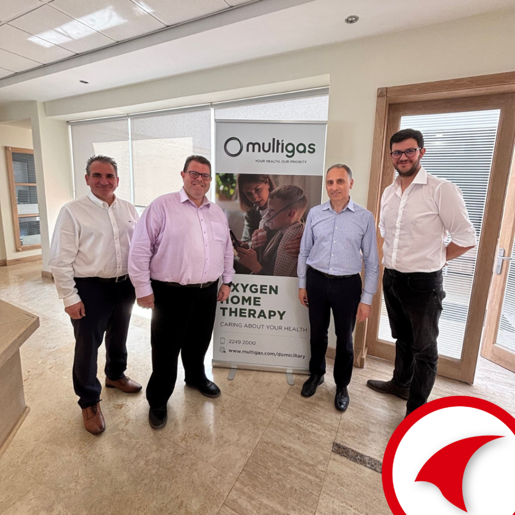 Four men standing in front of a Multigas “Oxygen Home Therapy” banner during a healthcare business collaboration meeting.